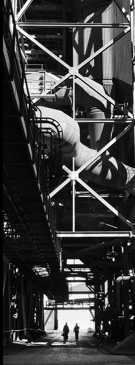 Two workers beneath the structures of the Andorra Thermal Power Station